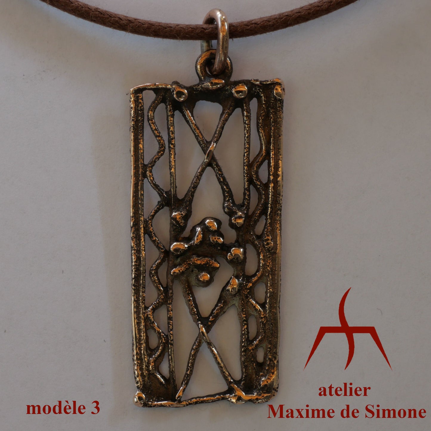 Pendentif en bronze découpé, décoré de motifs soudés